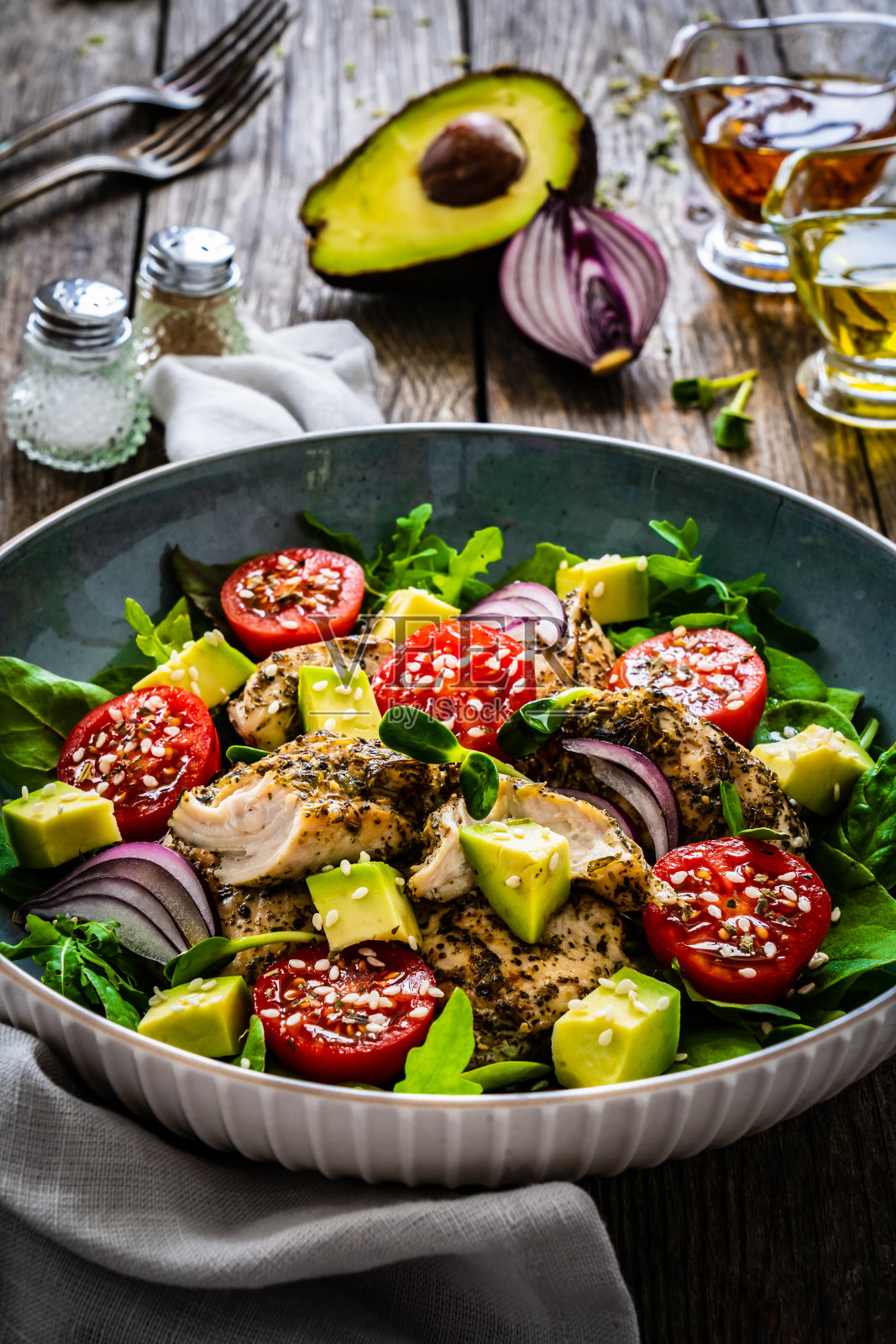 美味的沙拉——木桌上有鸡块、牛油果、芝麻、西红柿和新鲜的绿叶蔬菜照片摄影图片
