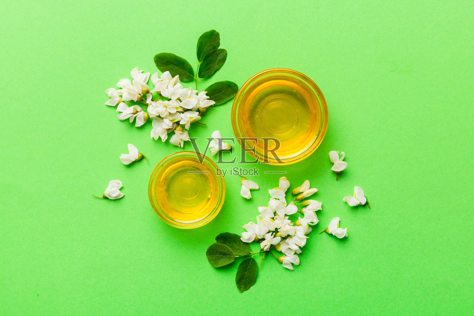 装有相思花和叶子的蜜罐。新鲜蜂蜜顶视图平躺照片摄影图片