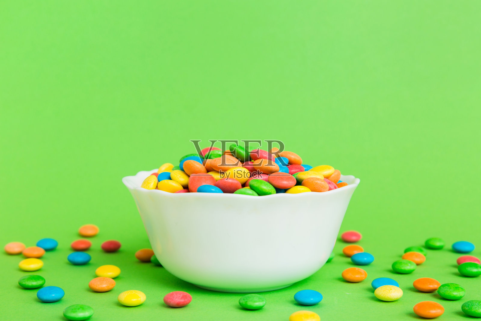 五颜六色的糖果放在碗里，背景是彩色的。生日和节日的概念。带复制空间的俯视图照片摄影图片