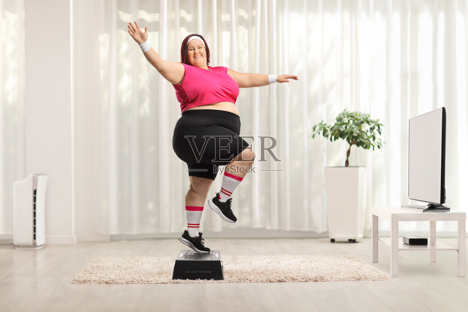 快乐的超重妇女在家里做有氧运动照片摄影图片