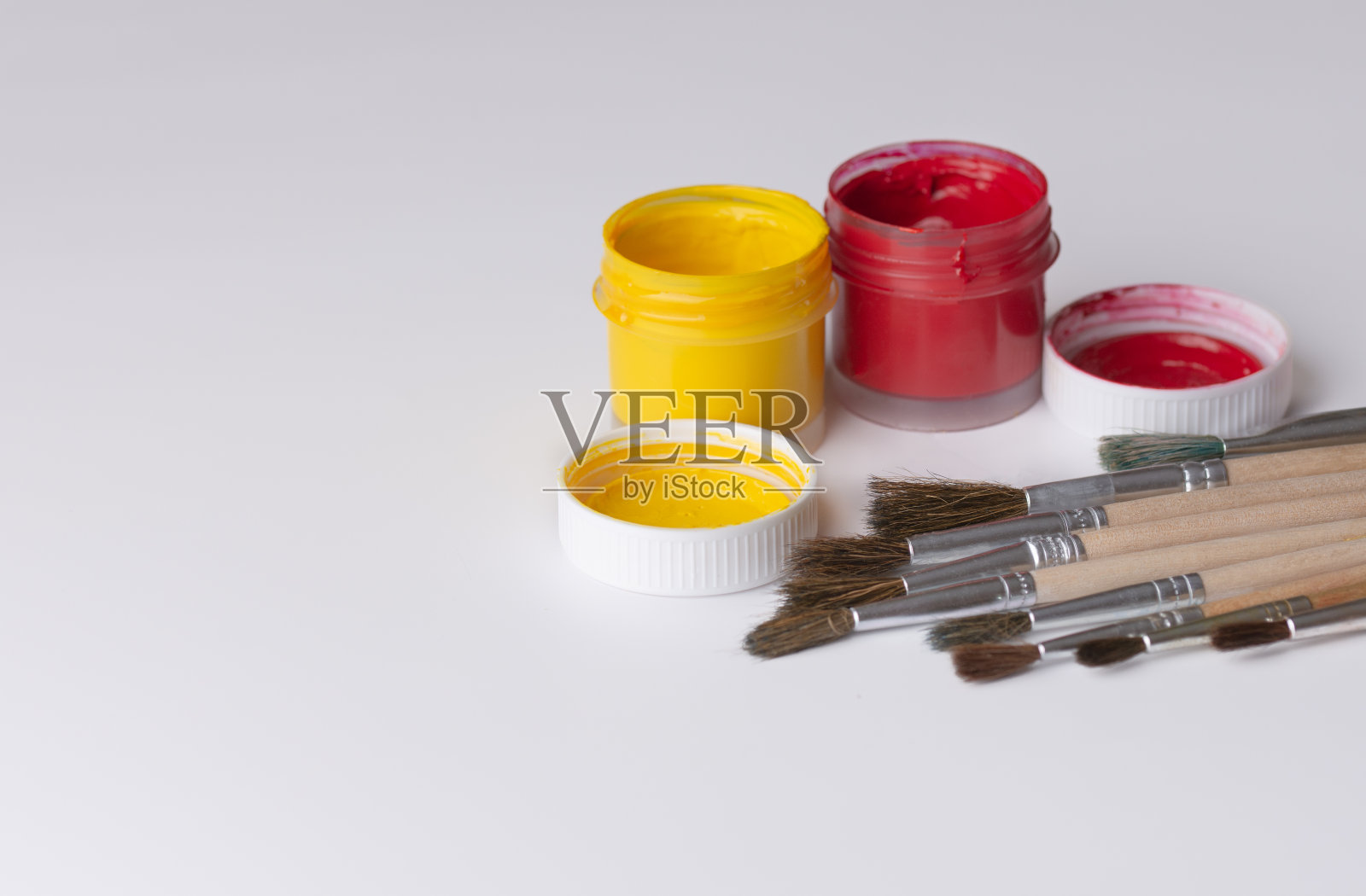绘画用的刷子和装有彩色水粉颜料的罐子照片摄影图片
