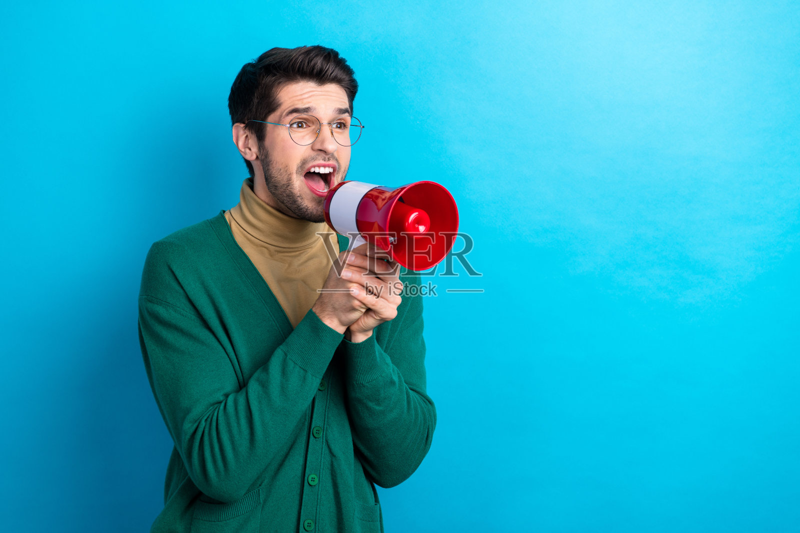 年轻男子的照片时髦的绿色毛衣尖叫扬声器扩音器空空间愤怒的示威孤立在青色背景照片摄影图片
