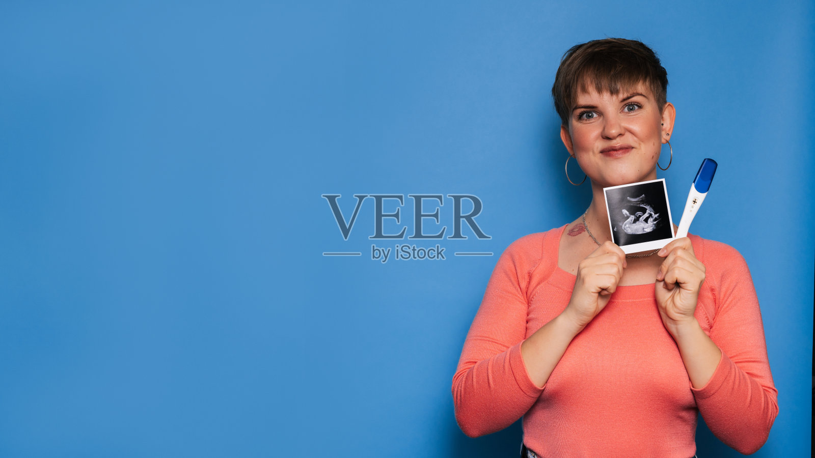 一位孕妇拿着一张婴儿的超声波图像和一张黄色背景的测试，一张母亲手中的超声波图像。复制空间。怀孕和产妇保健的概念。照片摄影图片