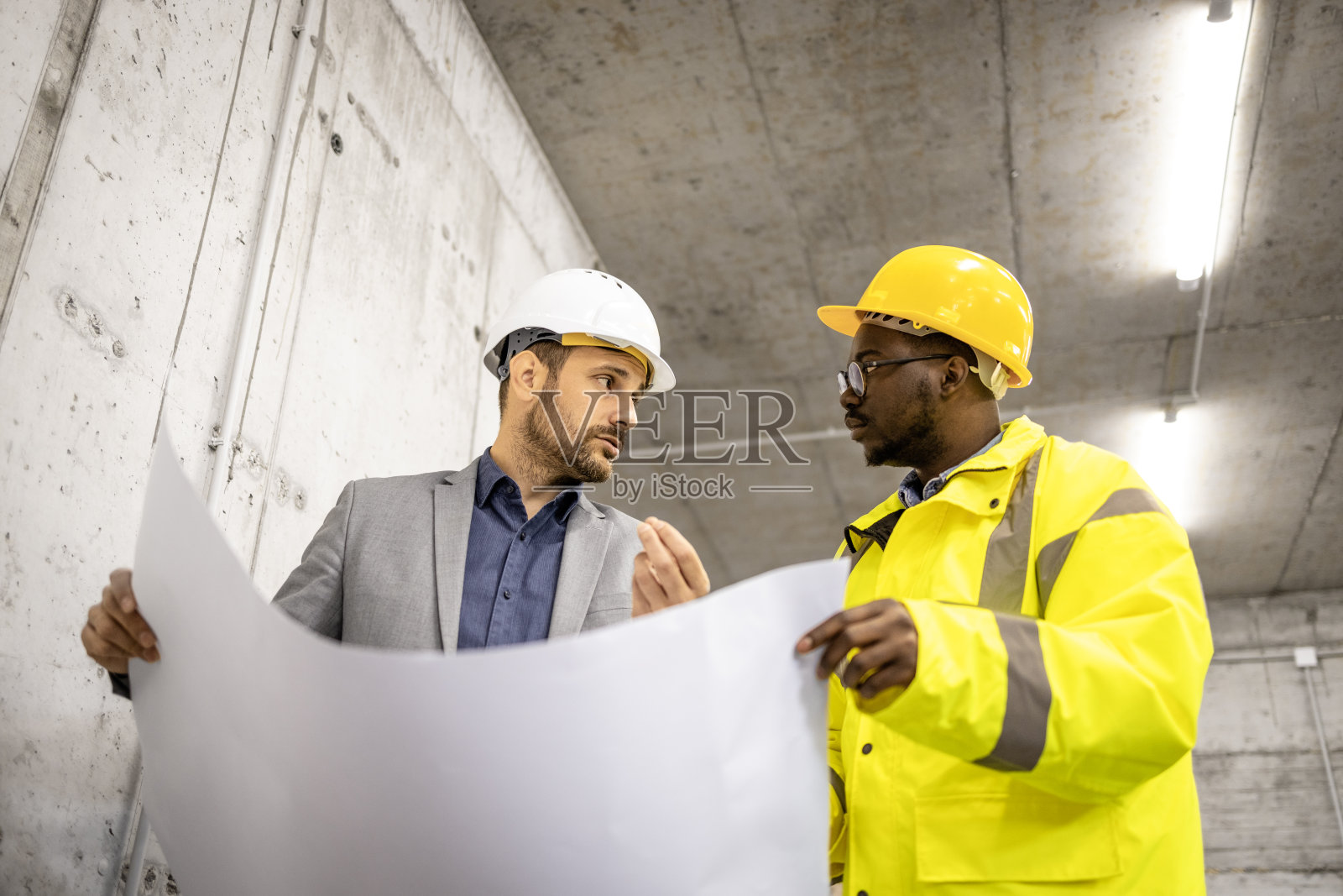 建筑工人和结构工程师一起负责新项目，并持有蓝图计划。照片摄影图片