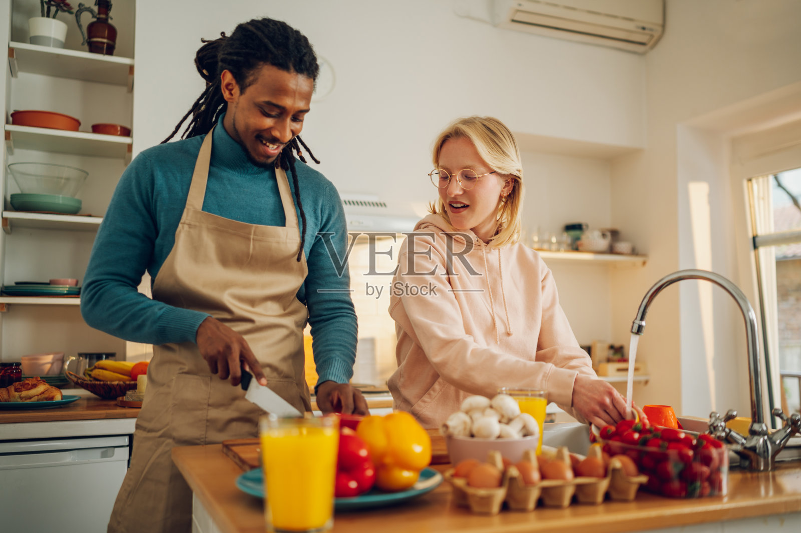 快乐的跨种族夫妇在家准备午餐和洗碗。照片摄影图片