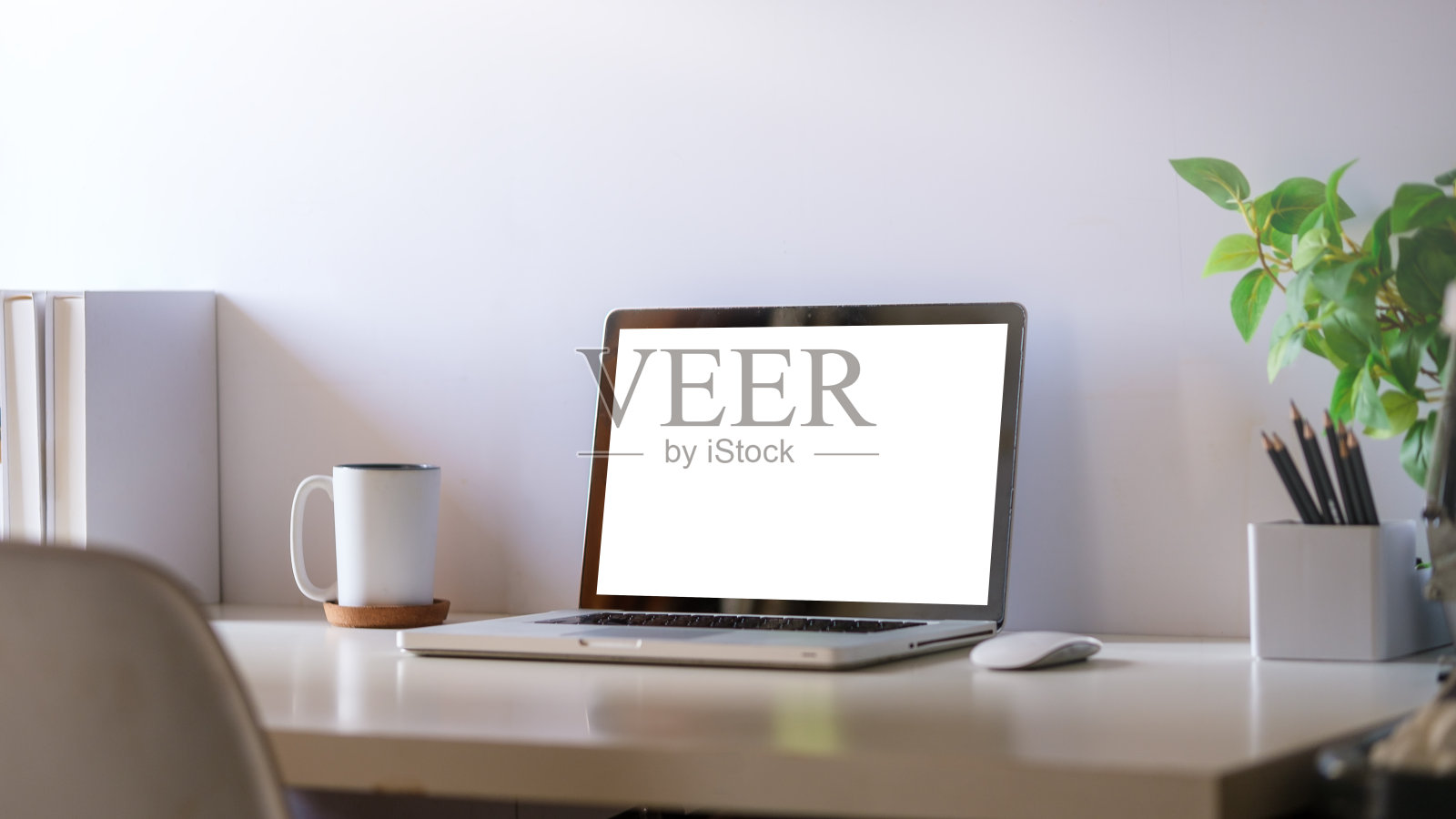 舒适的家庭办公室。白色桌子上的笔记本电脑、文具和盆栽。照片摄影图片