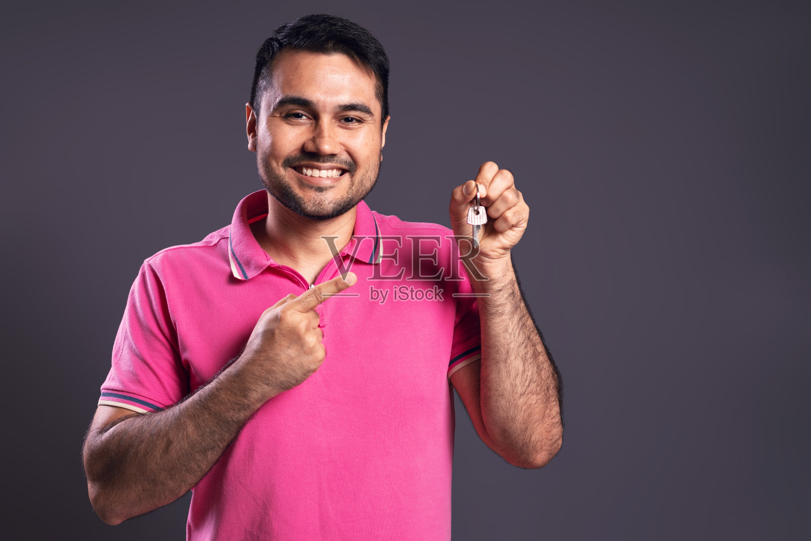 一个巴西人的肖像，穿着粉红色的polo衫，指着手里拿着的一串钥匙，开心地看着镜头，微笑着- bel<s:1> - par<e:1> -巴西照片摄影图片