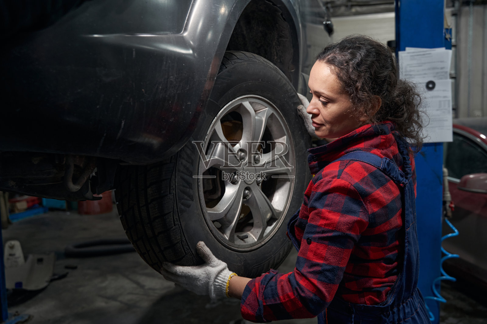 女汽车技师在维修服务站更换车轮照片摄影图片