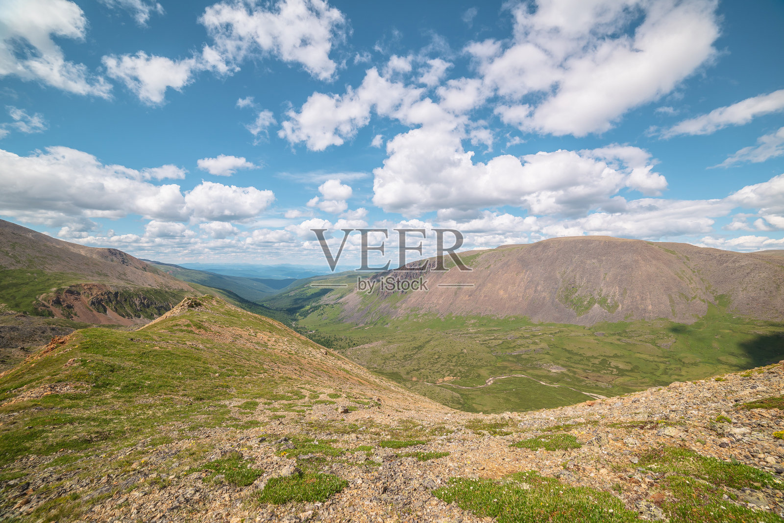 在多变的天气下，从山脊到绿色的森林山谷，在山脉和丘陵之间的地平线上。蓝天积云下的青山绿水。照片摄影图片