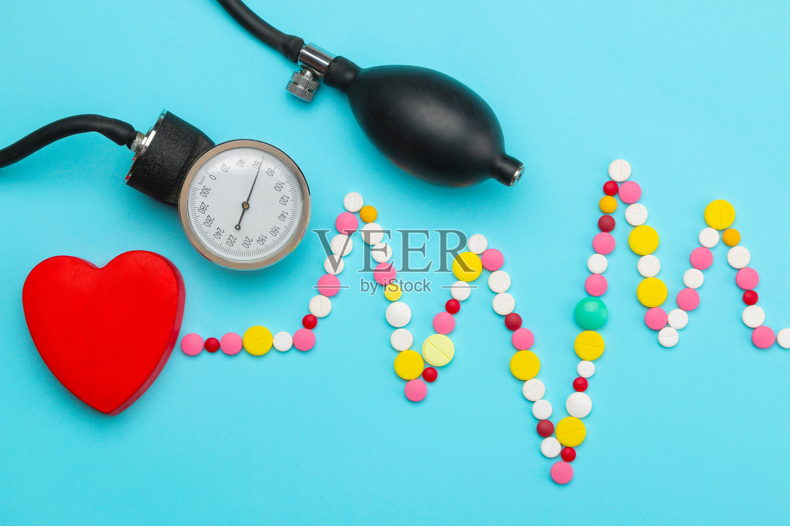 各种药片的心电图和蓝色背景上的红心。前视图。心脏病学和心脏病治疗。照片摄影图片
