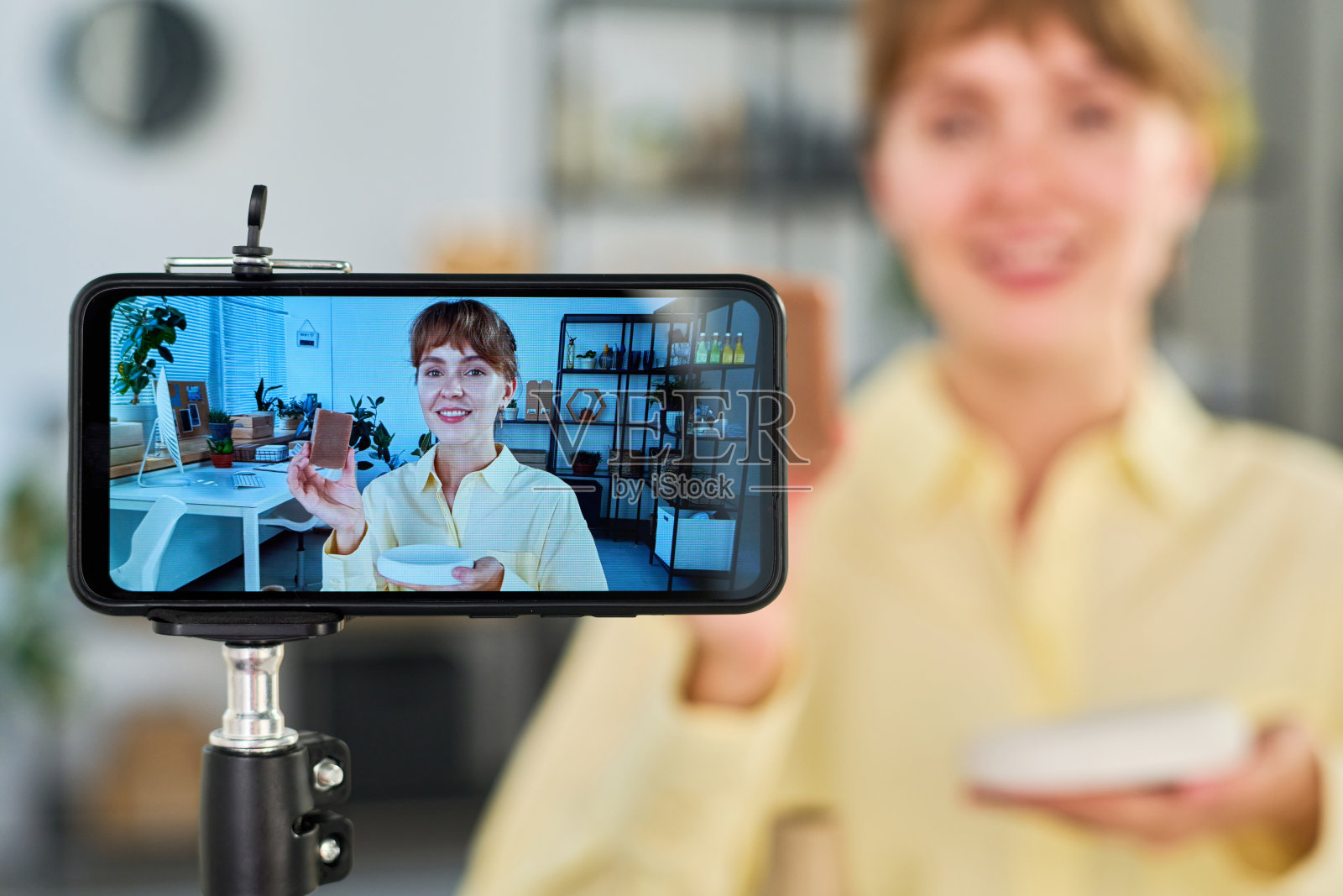 专注于智能手机屏幕，快乐的年轻女子拿着手工肥皂照片摄影图片