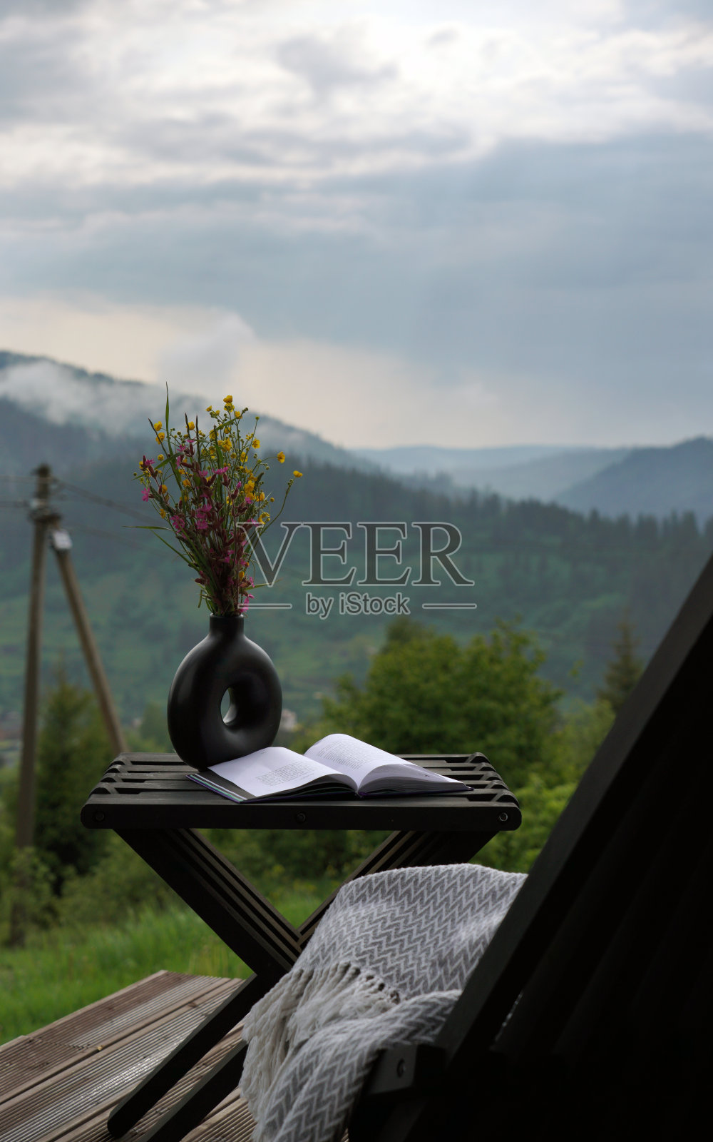 打开的书放在桌子上，花瓶上有山景照片摄影图片