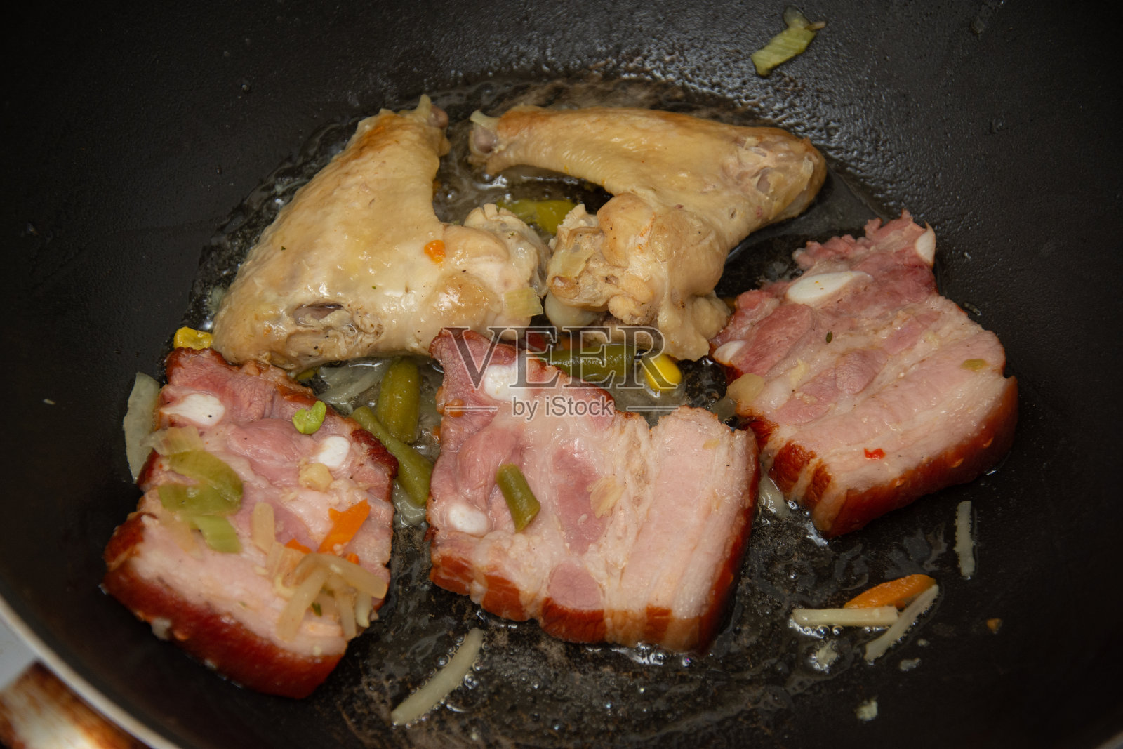 在锅里煎鸡翅和培根照片摄影图片