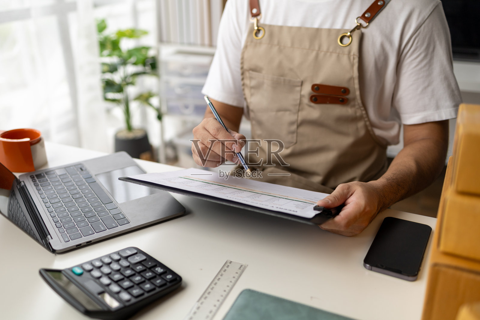 男子工作，在线商店老板检查网上网站的订单，与订购的客户确认订单，并打包发货。网上销售产品的概念。照片摄影图片