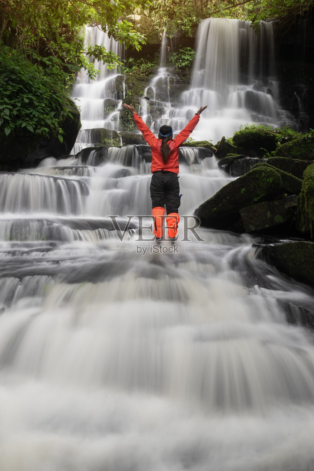 年轻的女背包客在看丛林中的瀑布。生态旅游概念形象旅游女孩。旅行者假期概念照片摄影图片