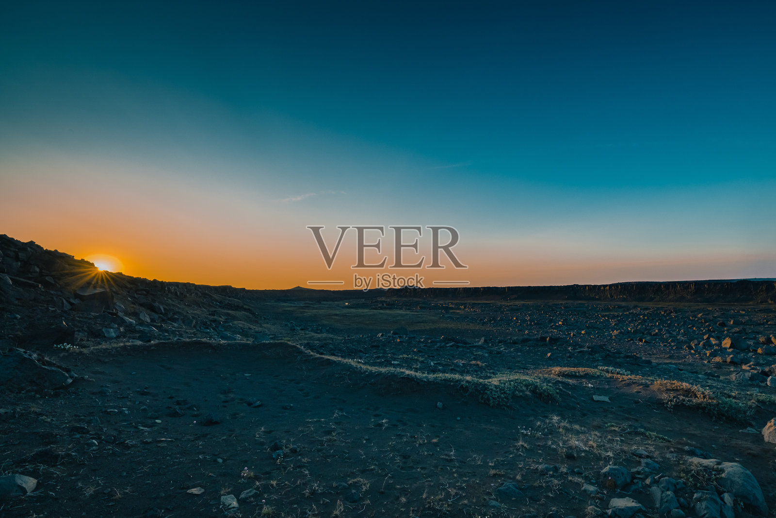 夏季日落时，冰岛的Dettifoss地区壮观的岩层，蓝色的岩石被美丽的橙色光包围，天空中闪耀着夕阳的光芒。照片摄影图片