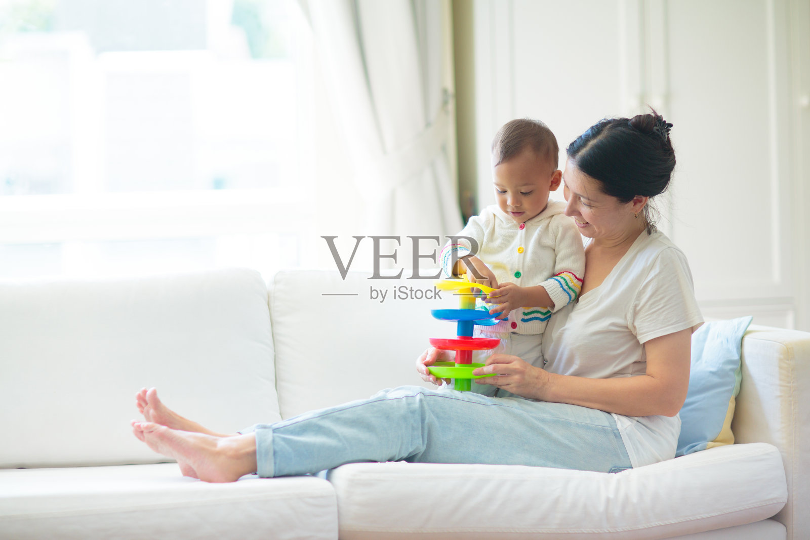 母亲和孩子躺在白色沙发上。照片摄影图片