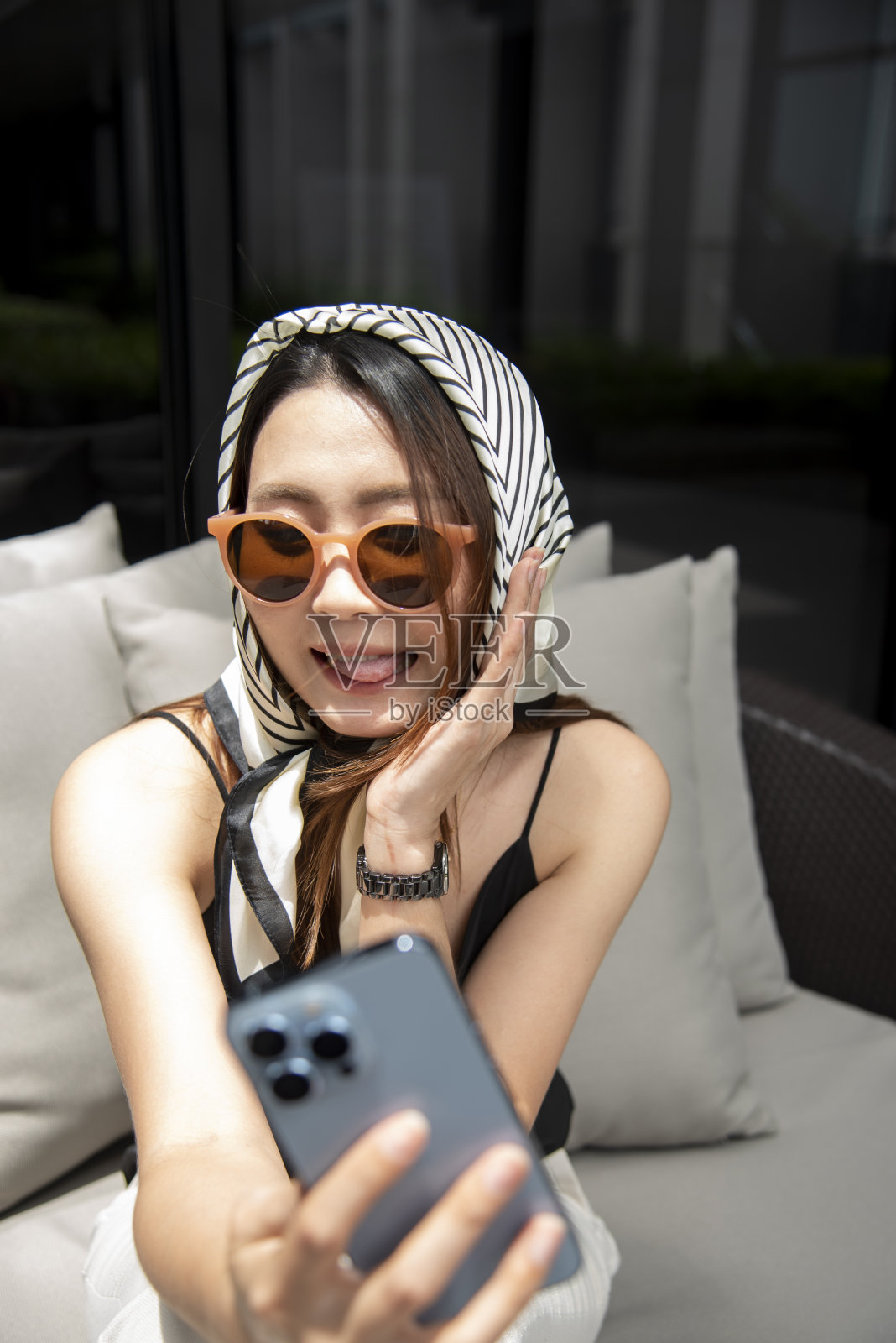 年轻快乐的微笑漂亮的女人坐在桌子上拿着智能手机使用手机现代科技照片摄影图片