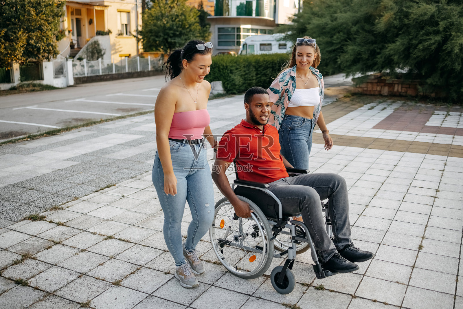 坐在轮椅上的年轻黑人男子和朋友们在公园外面消磨时光照片摄影图片