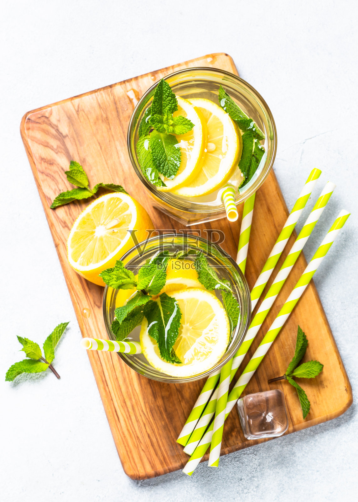 白色桌子上玻璃杯里的柠檬水。照片摄影图片