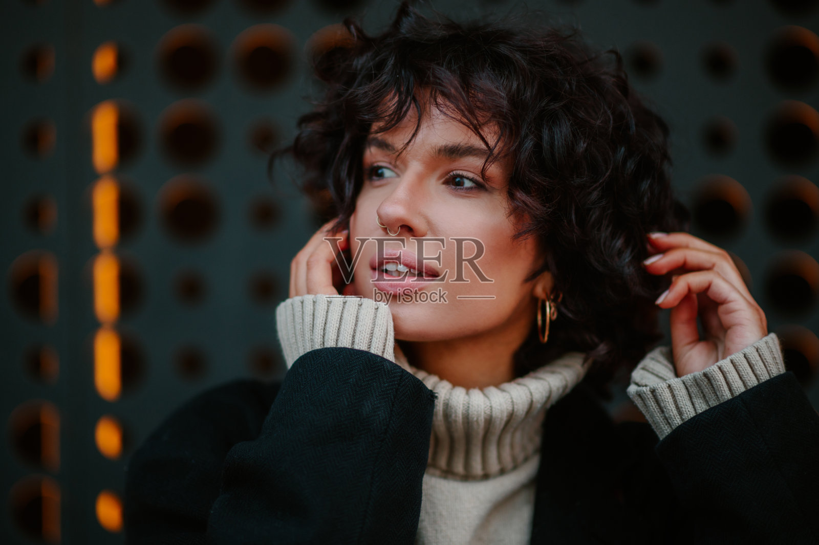 年轻女子用手指整理着头发，微笑着向一边看。照片摄影图片