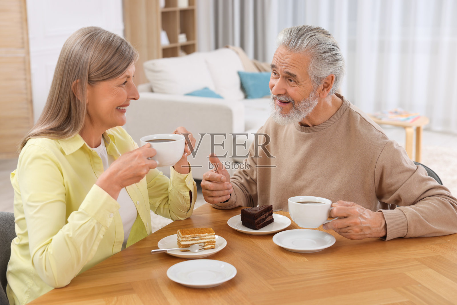 深情的老夫妇在房间的木桌上吃早餐照片摄影图片