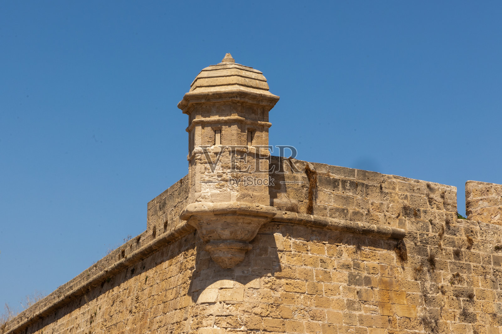 在一个晴朗的日子里，墙上的石头炮塔映衬着蓝天照片摄影图片