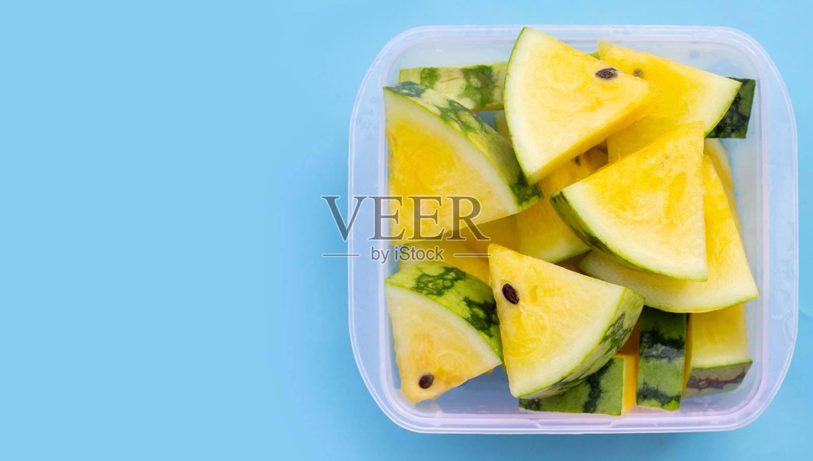 蓝色背景的黄色西瓜片。照片摄影图片