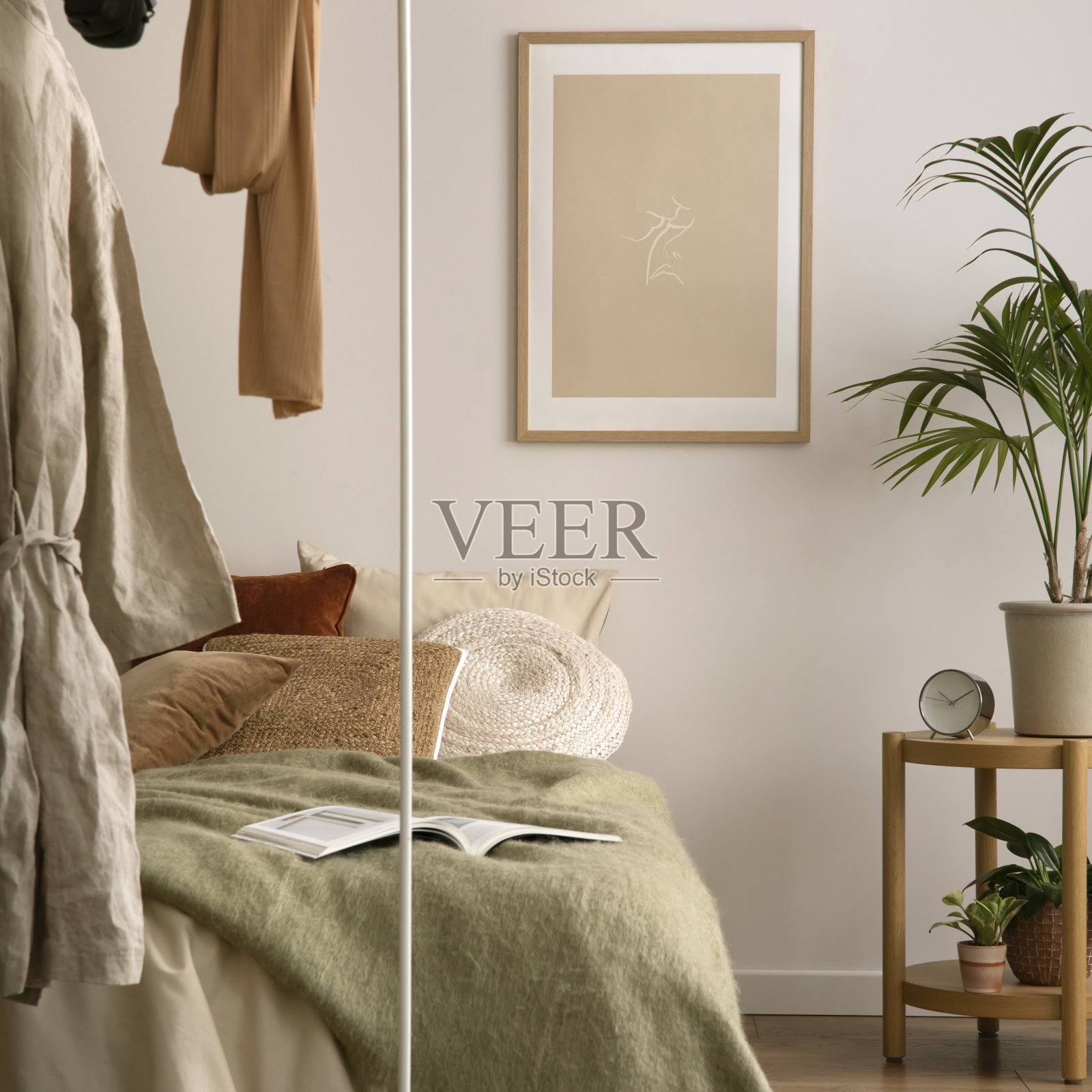 温馨舒适的卧室组成，模拟海报框架，绿色床上用品，木制床头柜，白色衣架，黑色篮子，灰色地毯和个人配件。家居装饰。模板。照片摄影图片