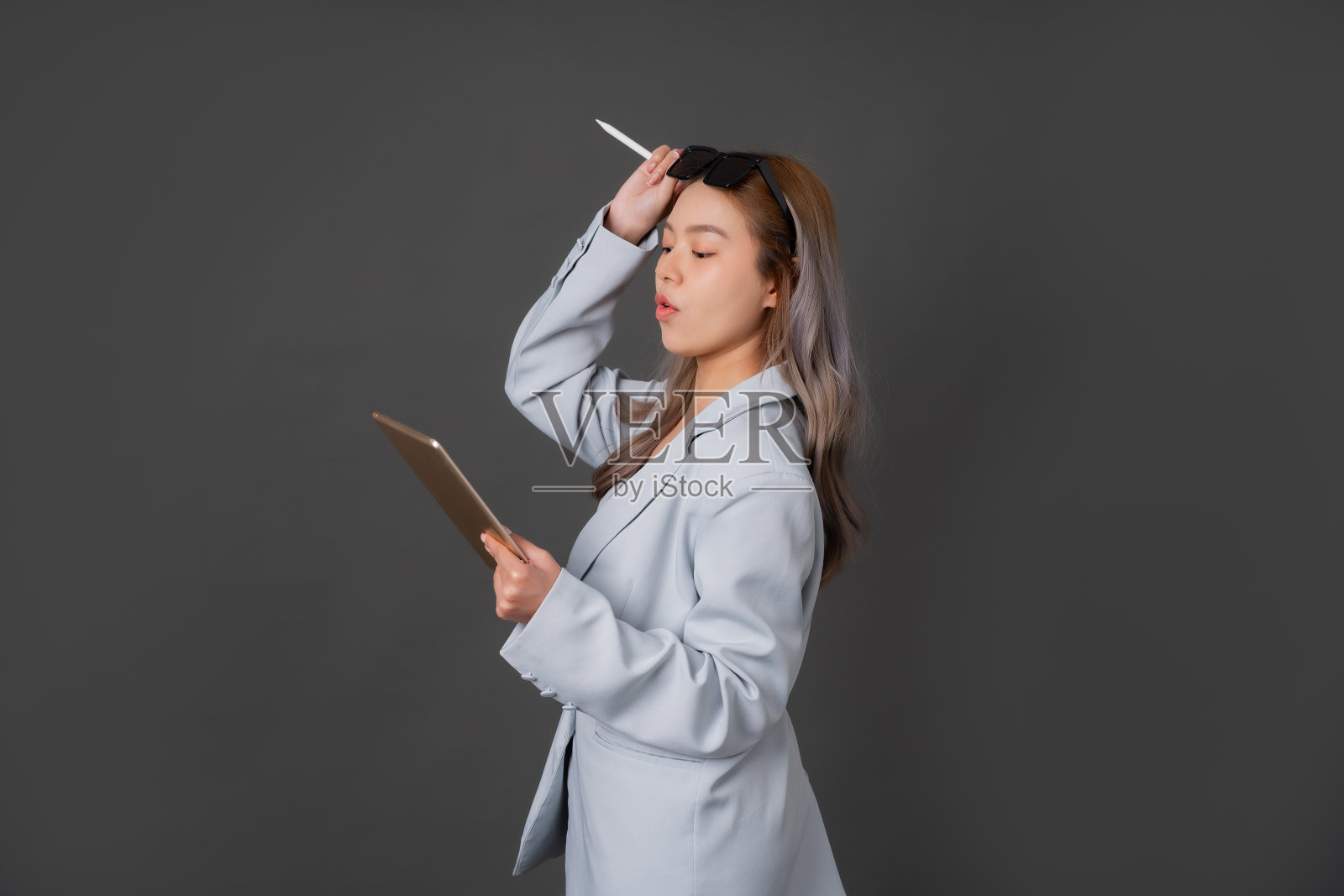 手持时尚眼镜的亚洲长发女高管在灰色背景工作室看平板照片摄影图片