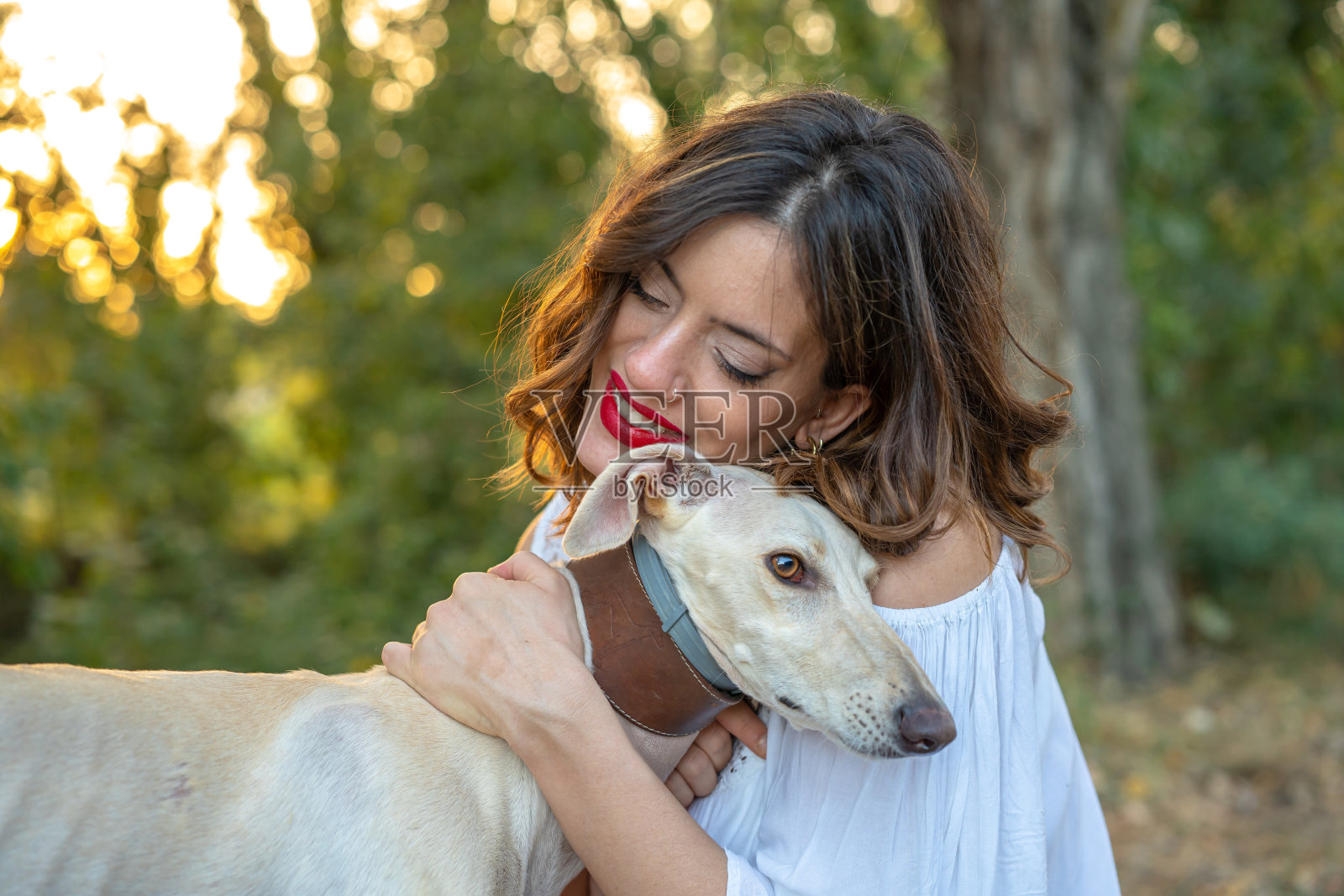 美丽的女人在夕阳下拥抱着她的宠物照片摄影图片