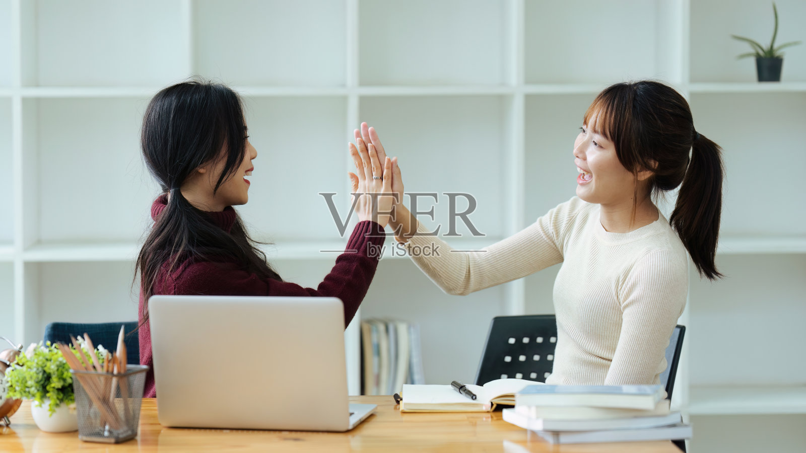 快乐的亚洲女职员与男同事击掌庆祝项目成功照片摄影图片
