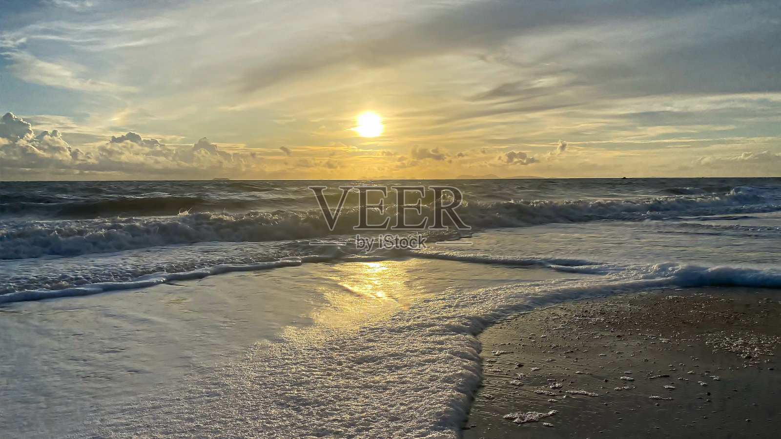 金色的日落在大海上，海浪在沙滩上照片摄影图片