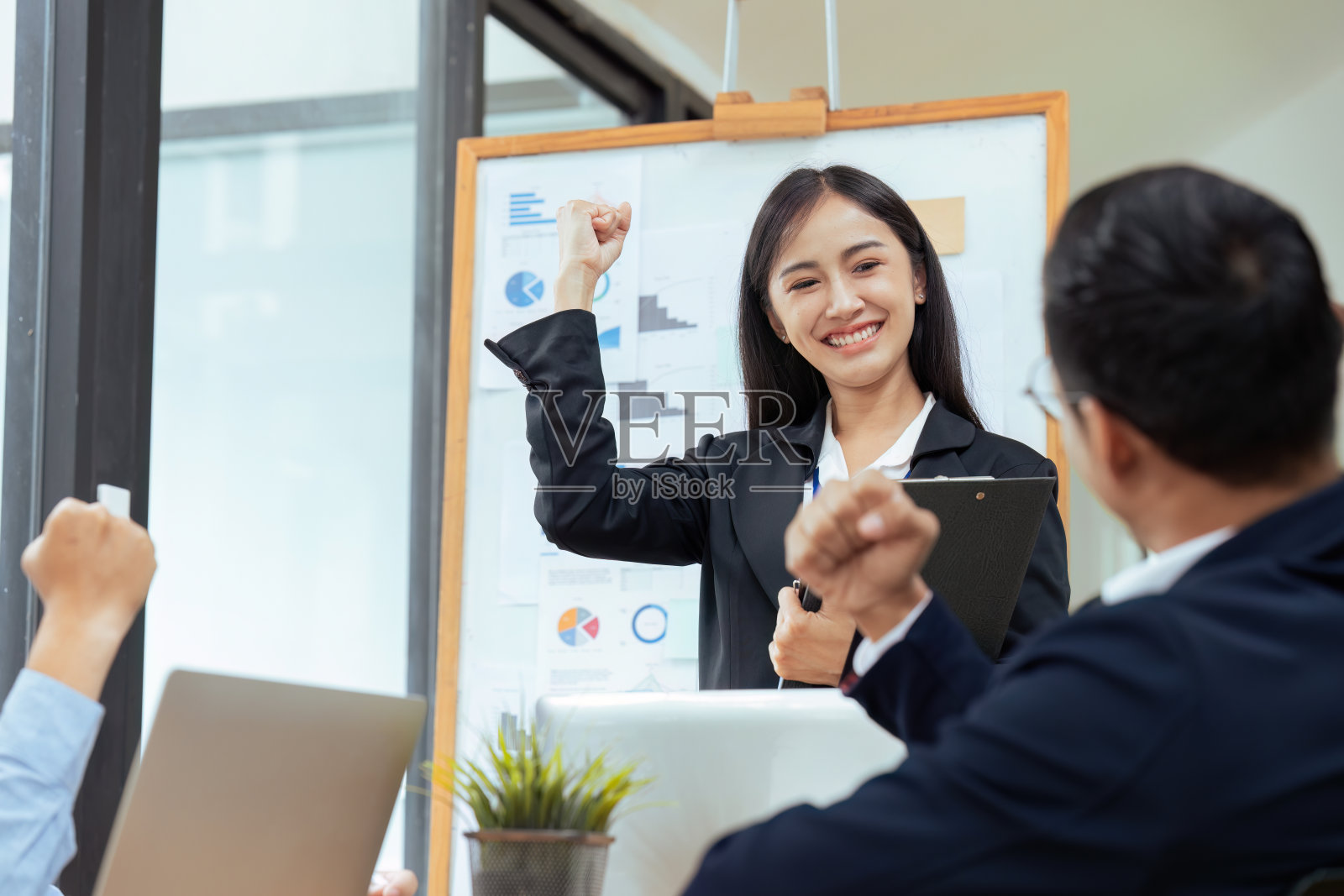 商务人士会微笑并举起双手，在与同事达成项目或协议成功后感到庆祝照片摄影图片