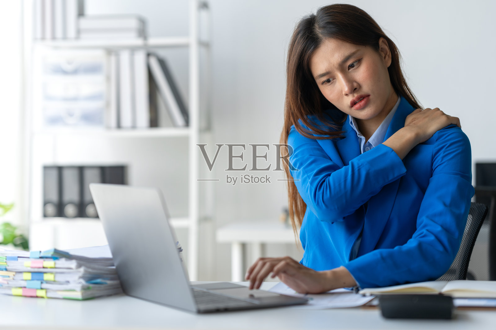 年轻女商人因长时间使用笔记本电脑工作，肩颈疼痛疲劳，办公室综合症神经系统疾病照片摄影图片