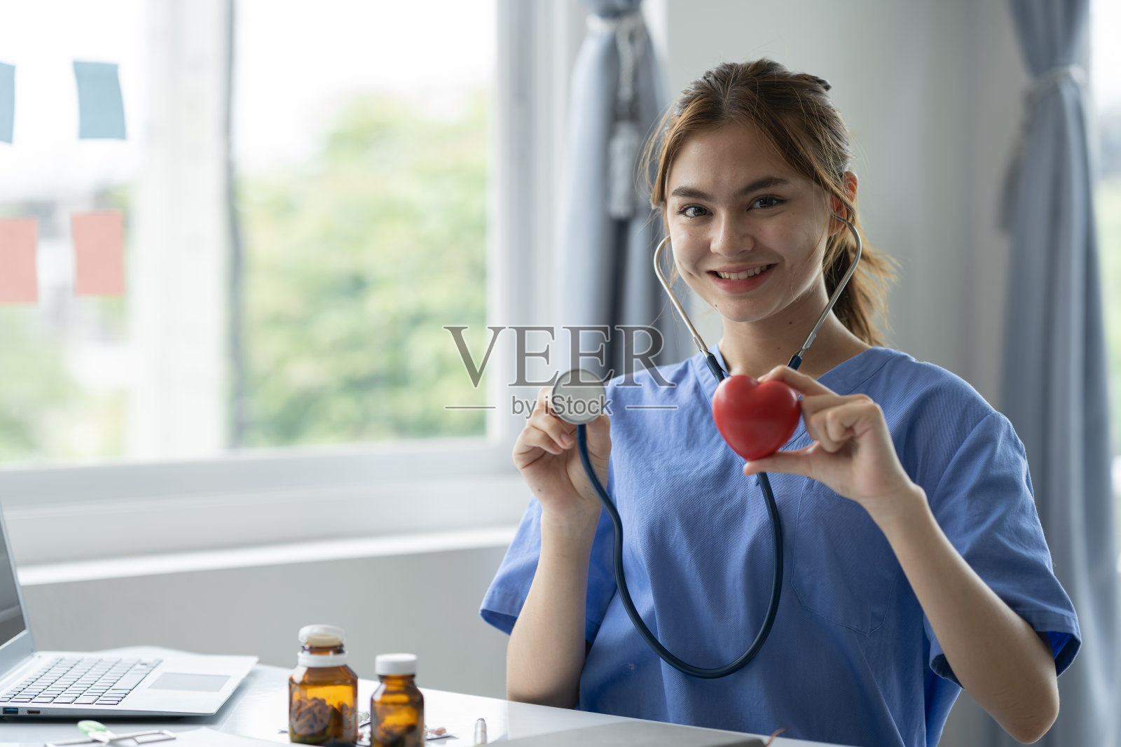 自信的医生带着听诊器，拿着红色的心脏和心电图。控制药物。治疗。治疗的概念。为心脏病，药物，人寿保险做计划。照片摄影图片
