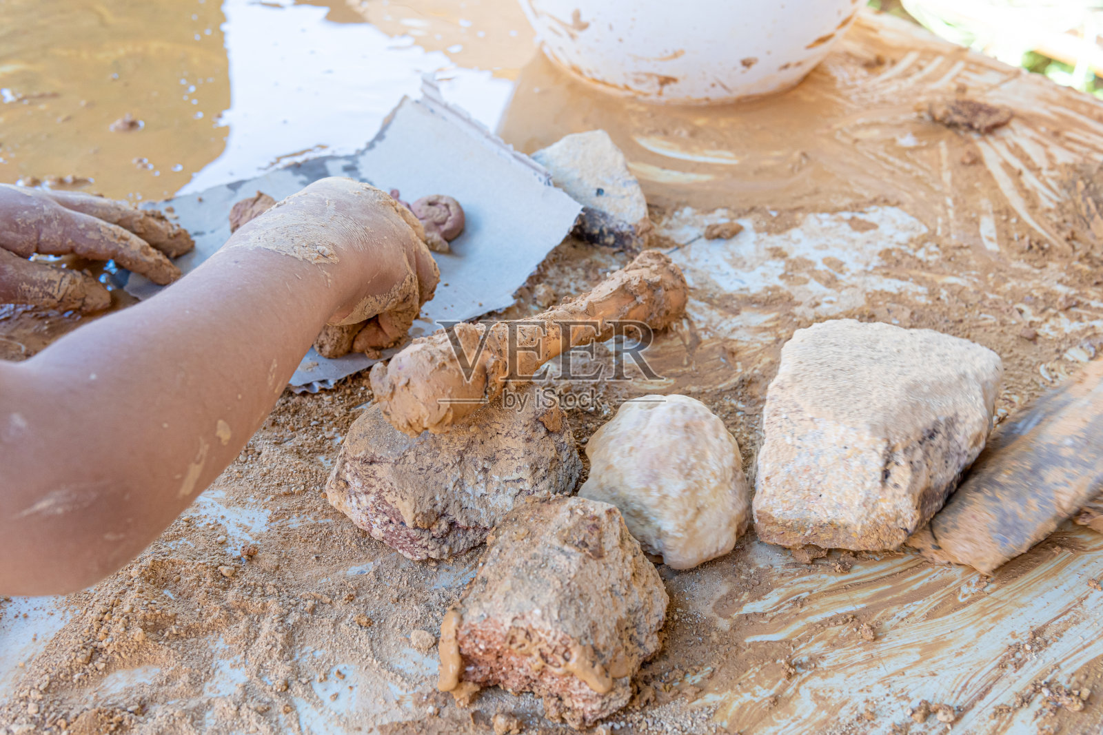 儿童用雕刻工具从破碎的粘土岩石中塑造天然粘土照片摄影图片