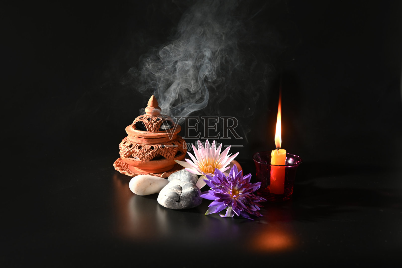 熏香在香炉上燃烧，在黑暗的背景上有蜡烛和美丽的花朵。宗教的概念照片摄影图片