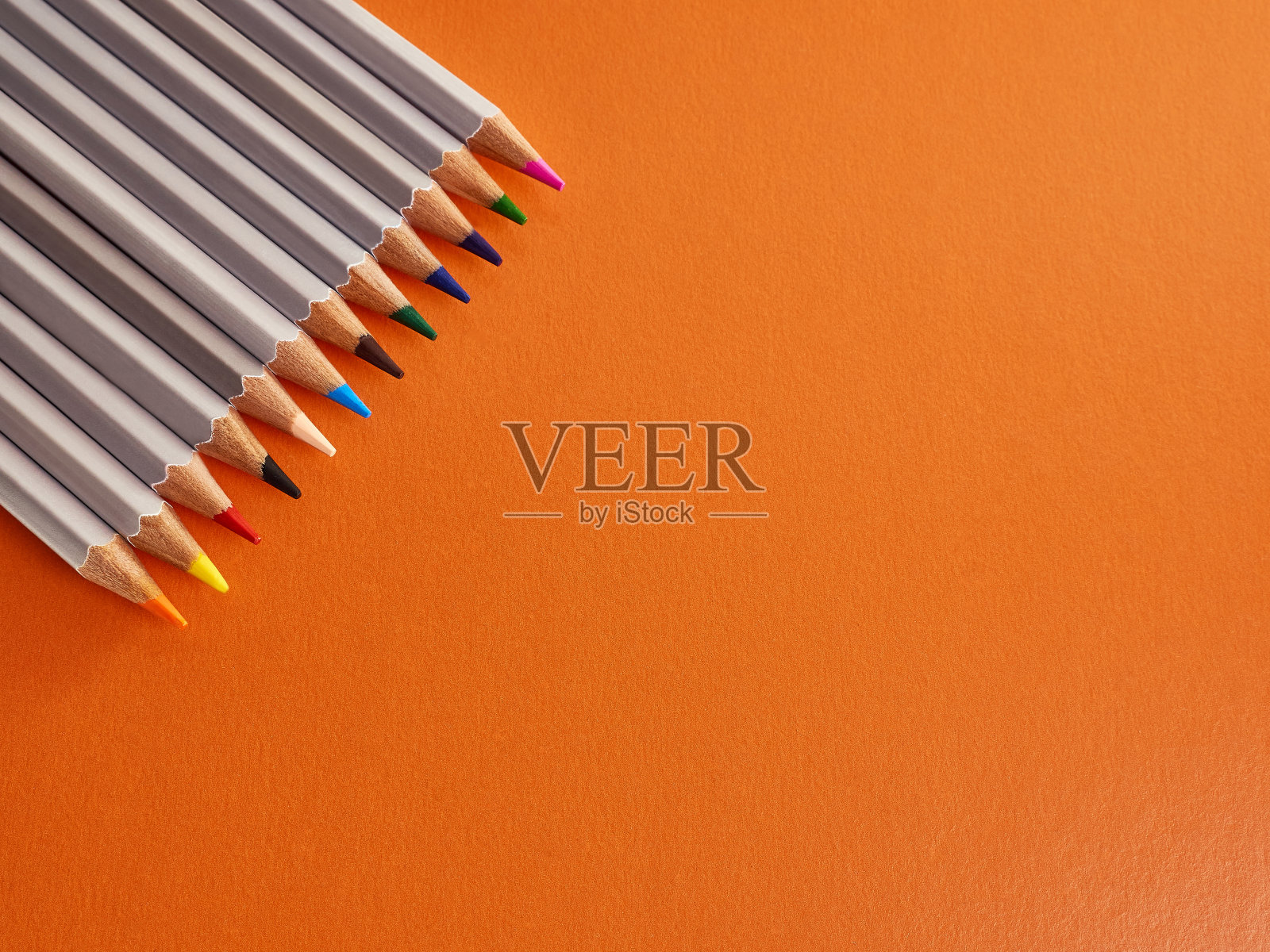 橙色背景上的一组彩色铅笔。创意和学习文具。照片摄影图片