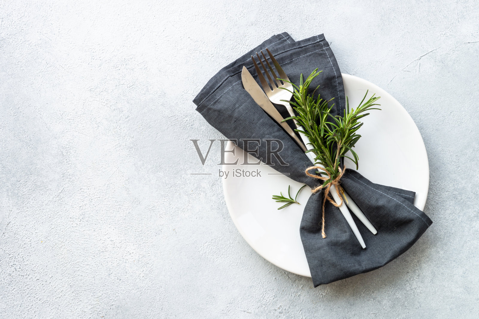 石桌上的白色盘子、餐具和餐巾。照片摄影图片