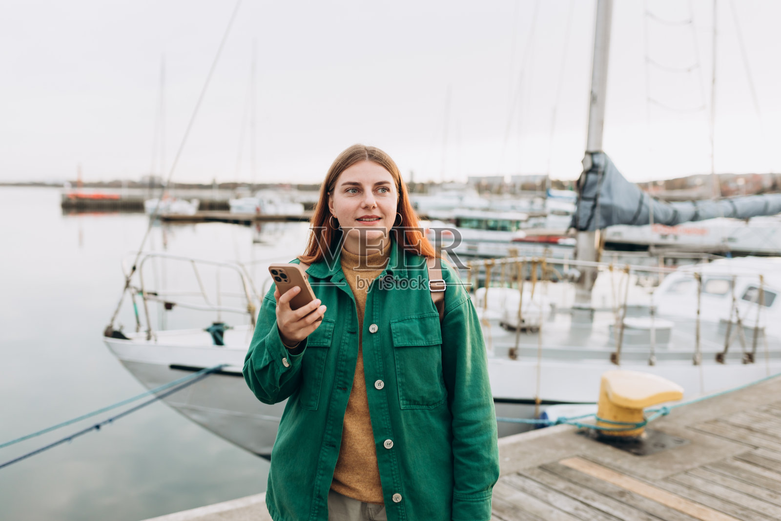 快乐的旅游女孩用智能手机在欧洲旅行。度假的概念，探索有趣的地方旅行租船。寻找地点，沿着海滨散步。照片摄影图片