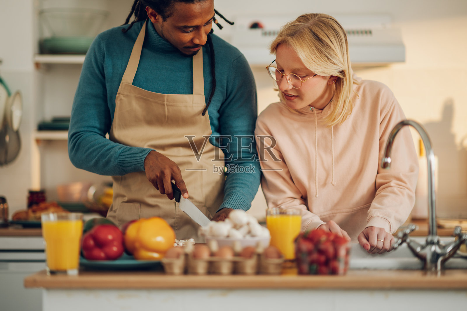 一对幸福的夫妇站在家里的厨房里做饭，洗餐具。照片摄影图片
