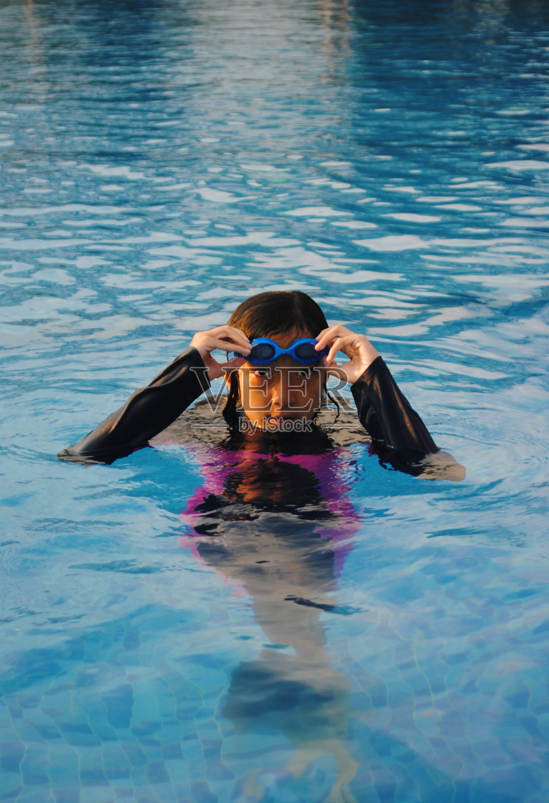 女孩在游泳池里游泳。提高温度。一个十几岁的女孩在游泳池里放松。照片摄影图片