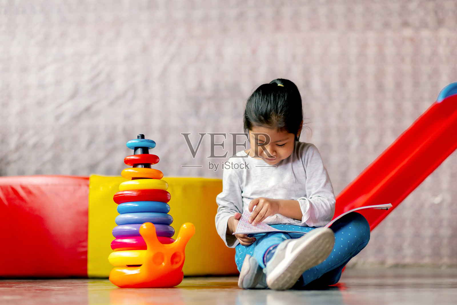 快乐的拉丁女孩在玩彩色的小圆圈塔。照片摄影图片