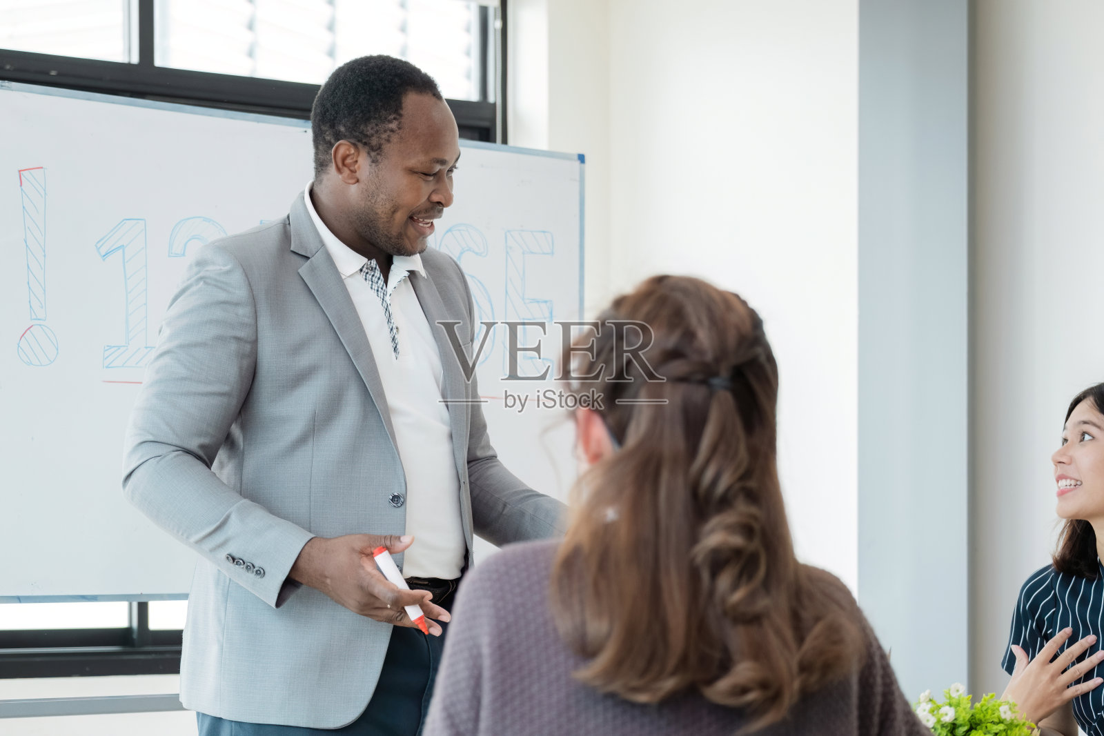 积极友好的非裔美国英语导师，为坐在教室桌子旁的不同国籍的学生提供语言课程照片摄影图片