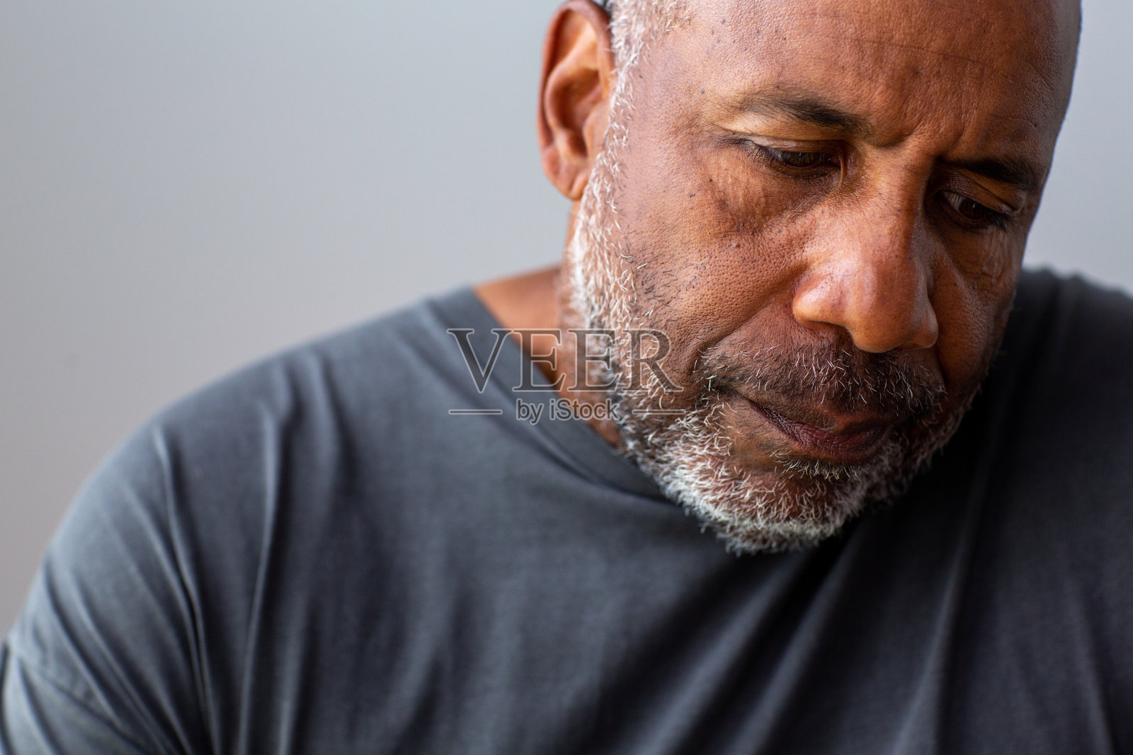 一个成熟男人的肖像，看起来很悲伤，远离镜头。照片摄影图片
