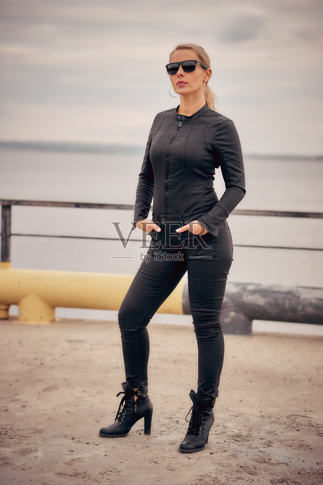 一个金发女人的肖像，穿着黑色牛仔连衣裤和太阳镜照片摄影图片