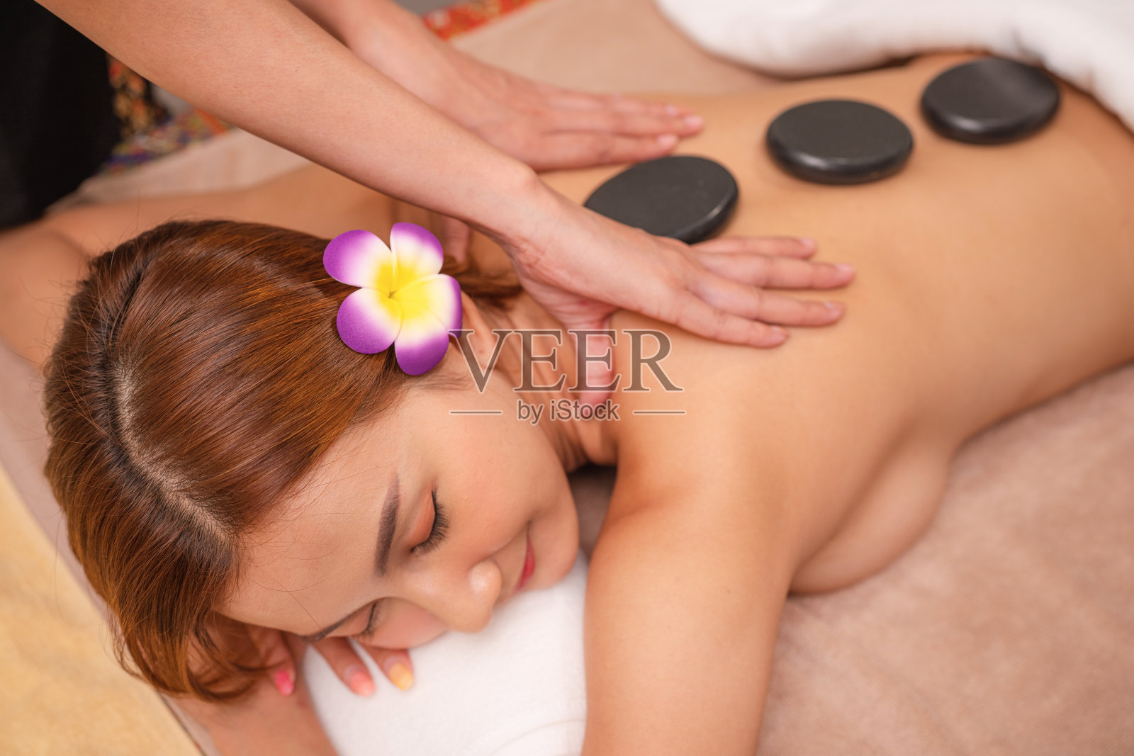 享受异国热石水疗按摩的女人。照片摄影图片