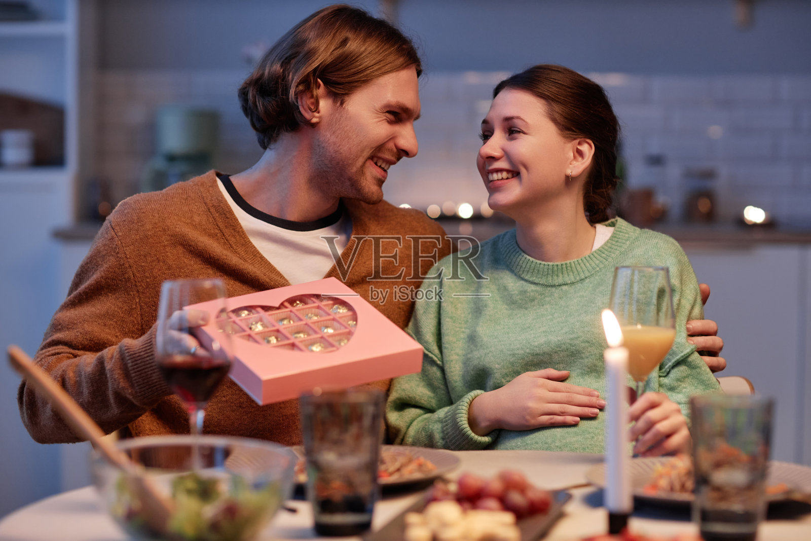 面带微笑，在结婚纪念日用礼物给怀孕的妻子带来惊喜的男人照片摄影图片