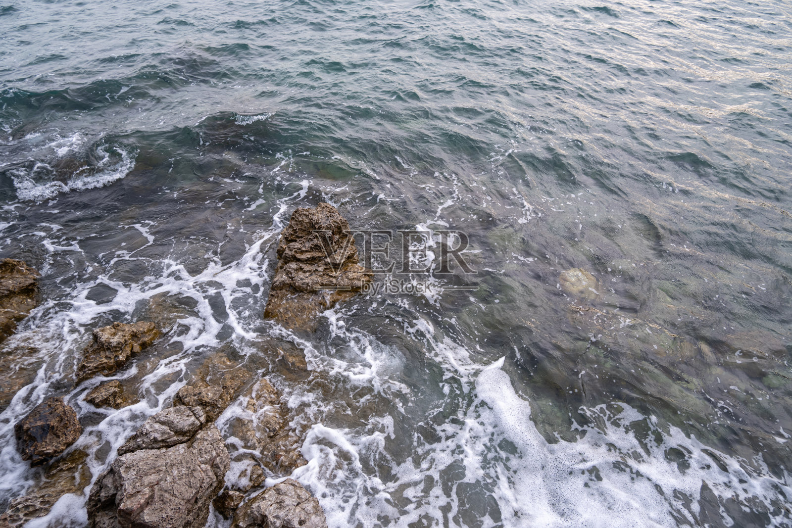 海边有许多岩石，被海浪咬着照片摄影图片